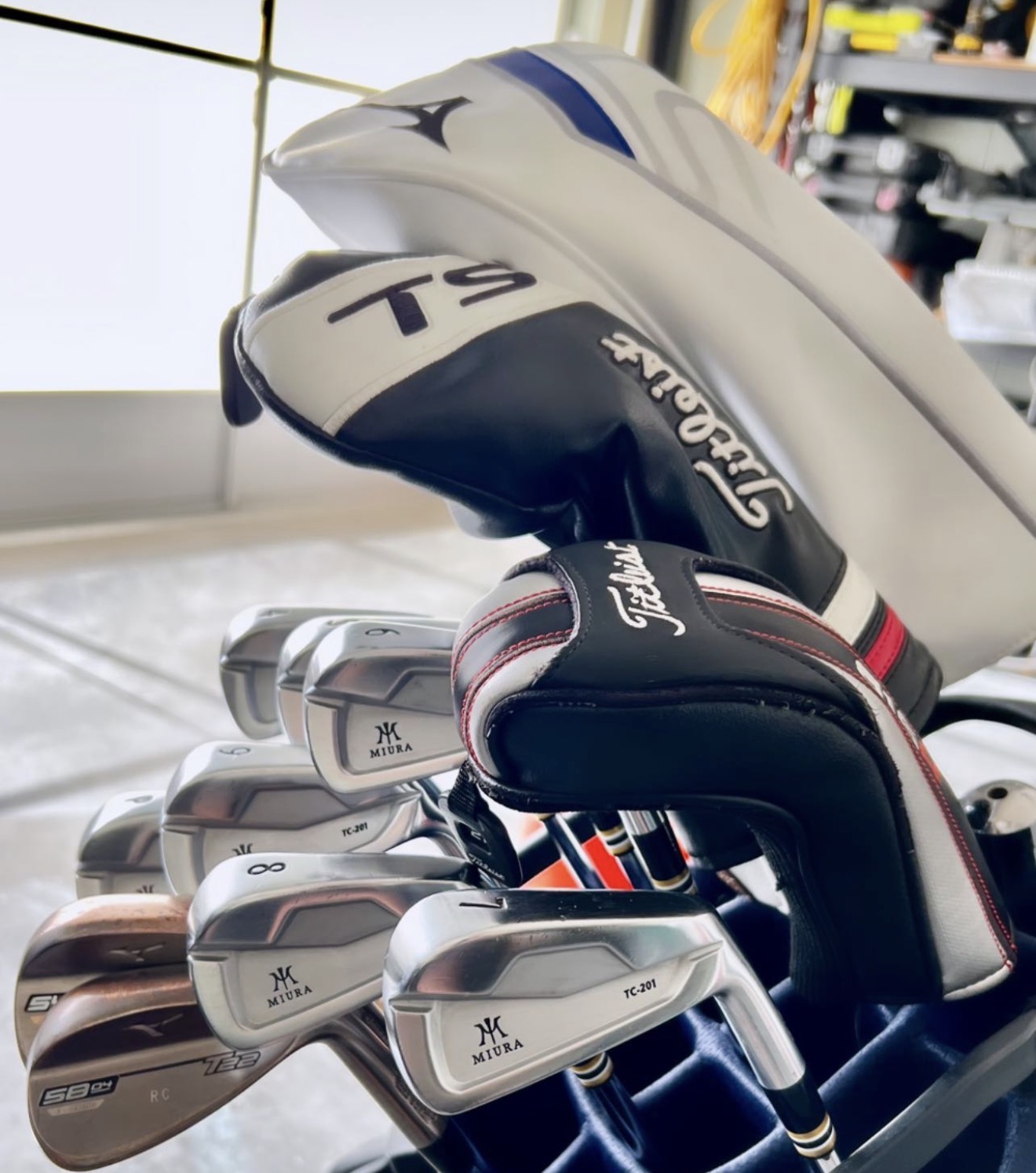 Miura TC-201 irons and a Mizuno wedge racked in a bag under Titleist headcovers