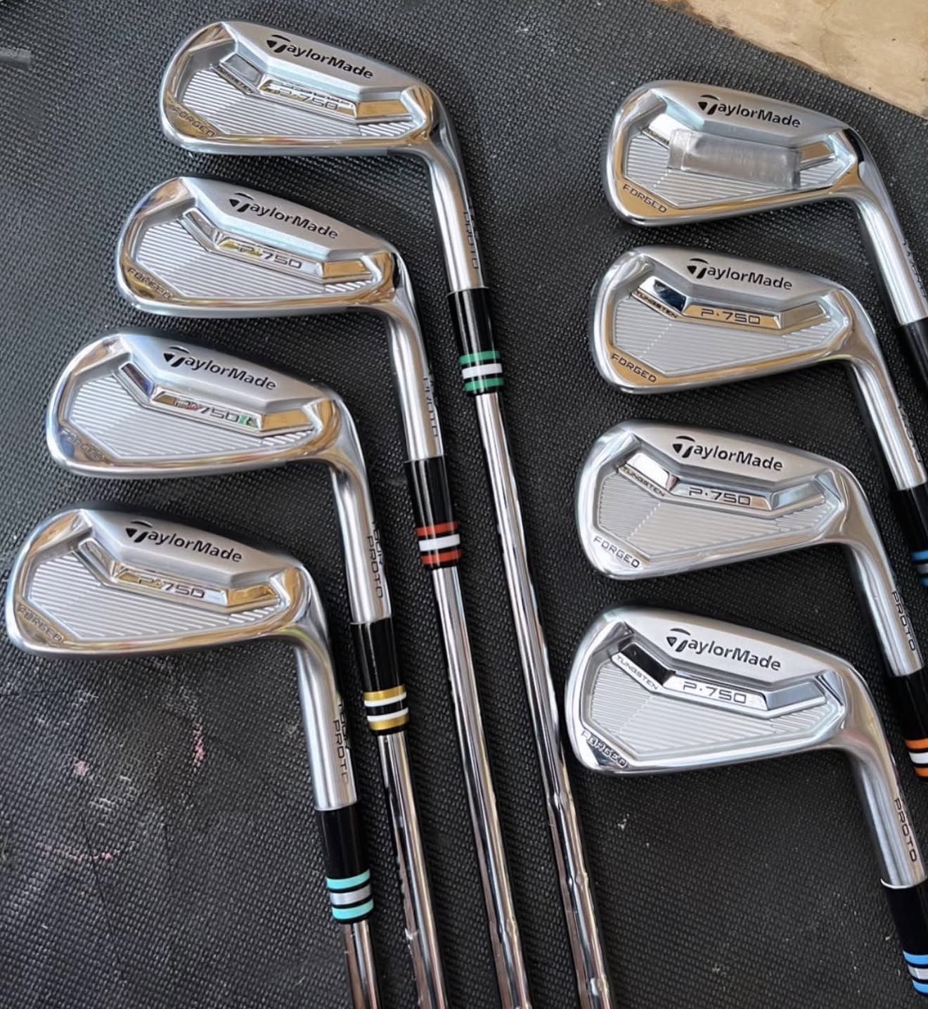 TaylorMade P-750 Forged proto irons laid out with mixed color ferrule bands